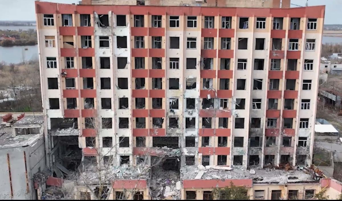 A shell-damaged apartment block in Kherson with its windows blown out and lower floors collapsed