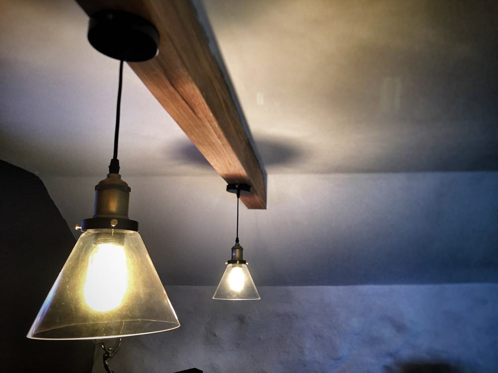 Two glass pendant lights hanging from a wooden beam